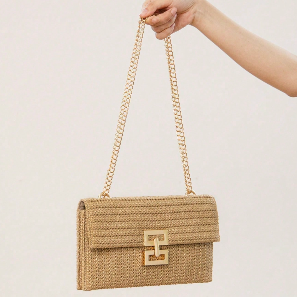 Woven handbag with a chain strap held by a hand against a light background
