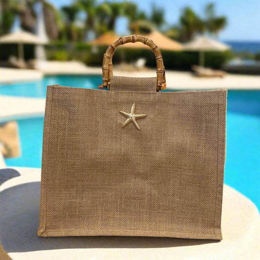Jute bag with bamboo handle and starfish charm on a wicker surface.
